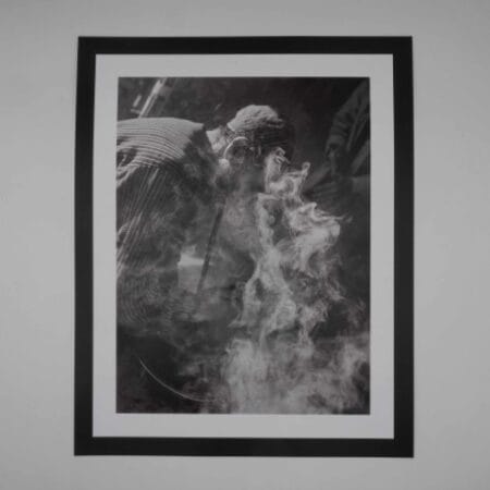 Black and white image of an Afghan man smoking hash through a traditional hookah