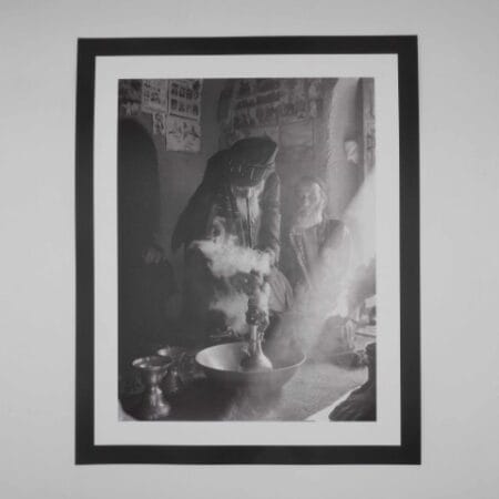 Black and white image of an Afghan man smoking hash through a traditional hookah
