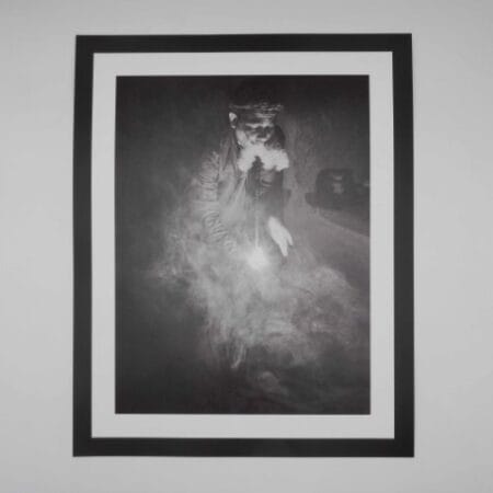 Black and white image of an Afghan man smoking hash through a traditional hookah